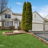 a white house with a small yard and large trees
