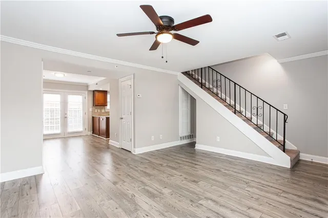 a view of an empty room with wooden floor and a ceiling fan