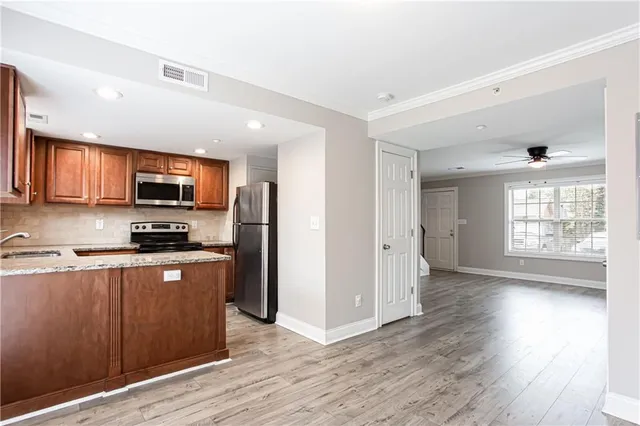 a kitchen with stainless steel appliances granite countertop wooden cabinets a stove a sink and a microwave