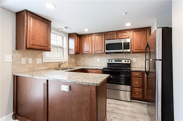 a kitchen with granite countertop a stove top oven and refrigerator