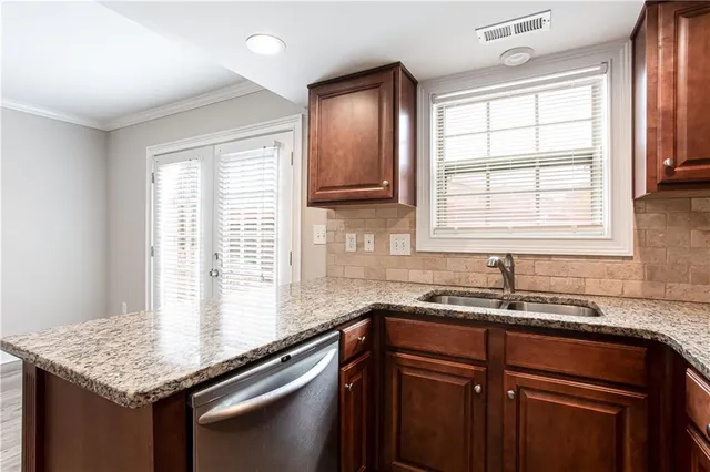 a kitchen with granite countertop a sink window and cabinets