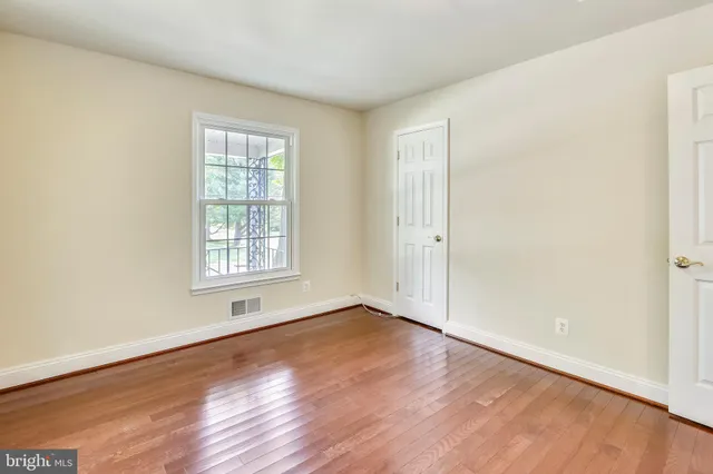 an empty room with wooden floor chandelier and windows