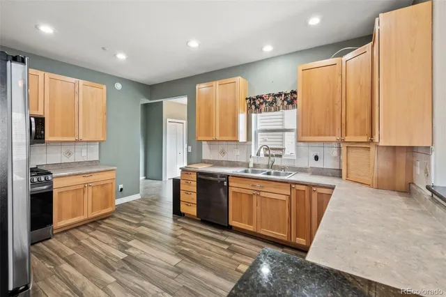 a large kitchen with stainless steel appliances granite countertop a stove a sink dishwasher and a refrigerator with wooden floor