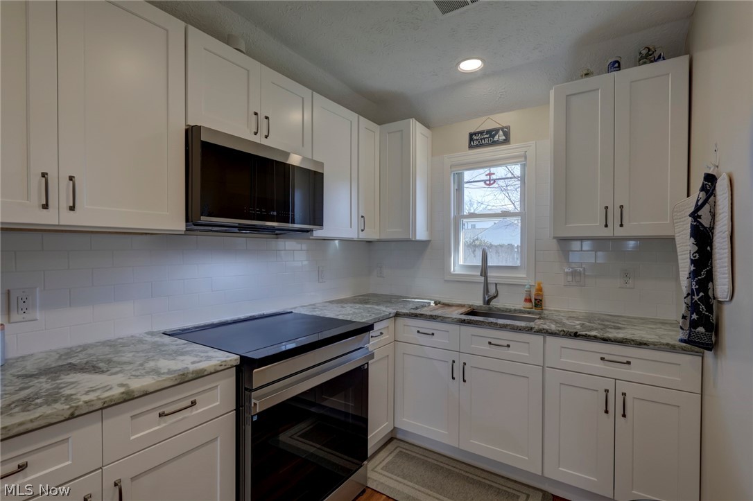 189 Harcourt Road Vermilion, OH 44089 - Photo 11 of 36 Kitchen with stainless steel appliances, white cabinets, light stone countertops, and recessed lighting
