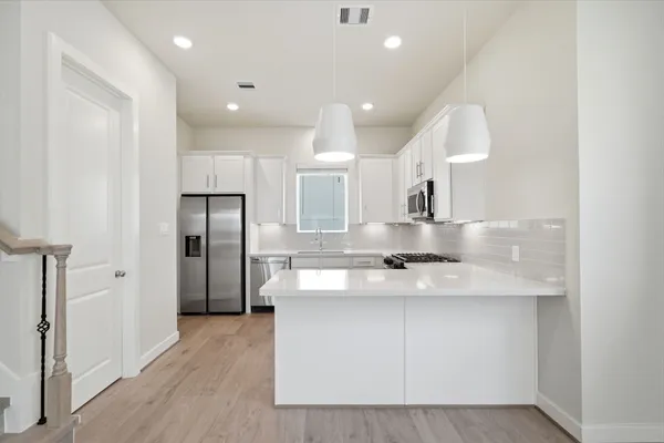 a kitchen with granite countertop white cabinets and stainless steel appliances