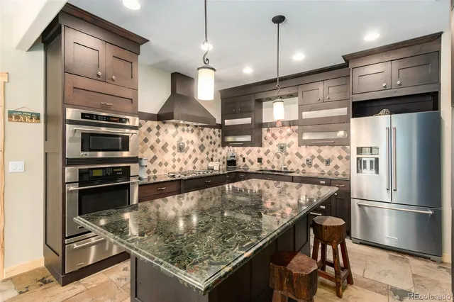 a kitchen with stainless steel appliances granite countertop a refrigerator a stove and a sink