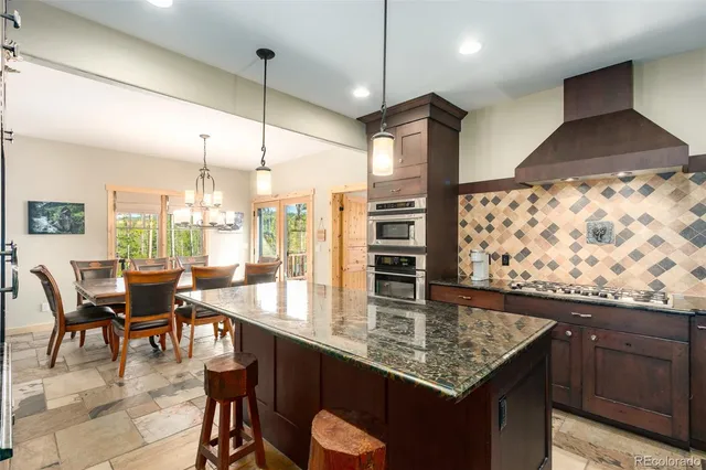 a kitchen with stainless steel appliances granite countertop sink stove and dining table