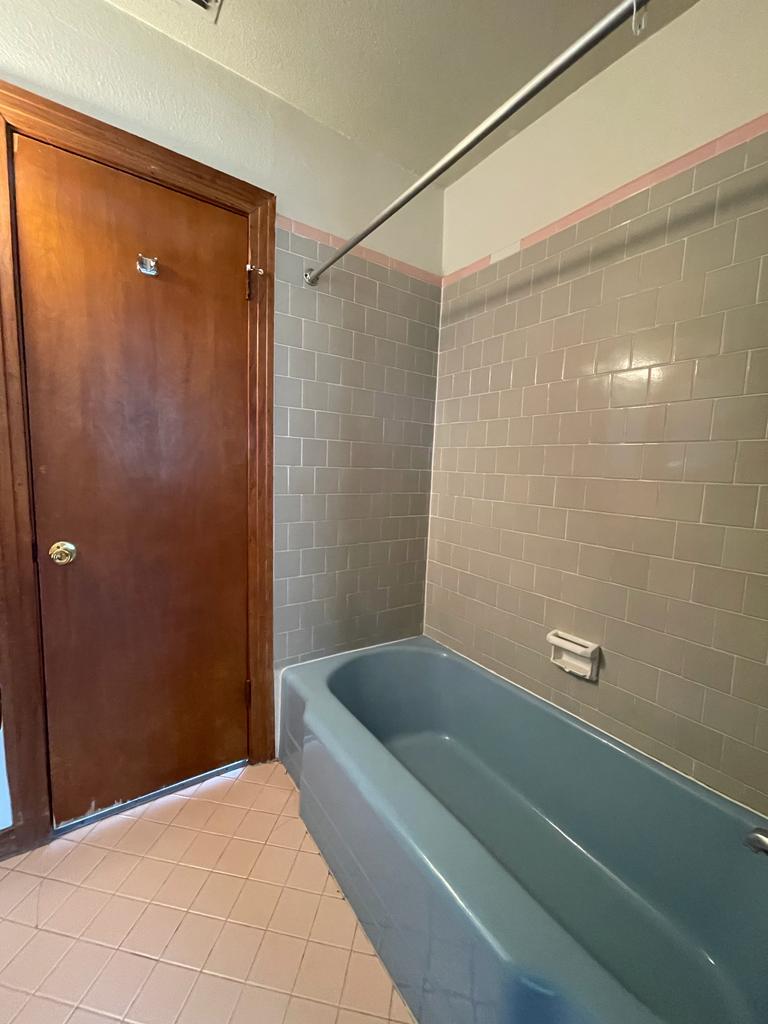 108 Austin Street, Unit B Kyle, TX 78640 - Photo 11 of 14 A classic bathtub set against tiled walls offers a clean and functional bathing space.