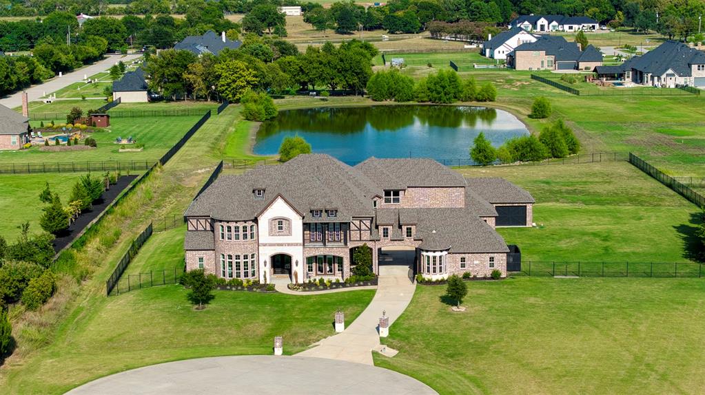 A sprawling property featuring a large residence with a multi-gabled roof and an expansive lawn