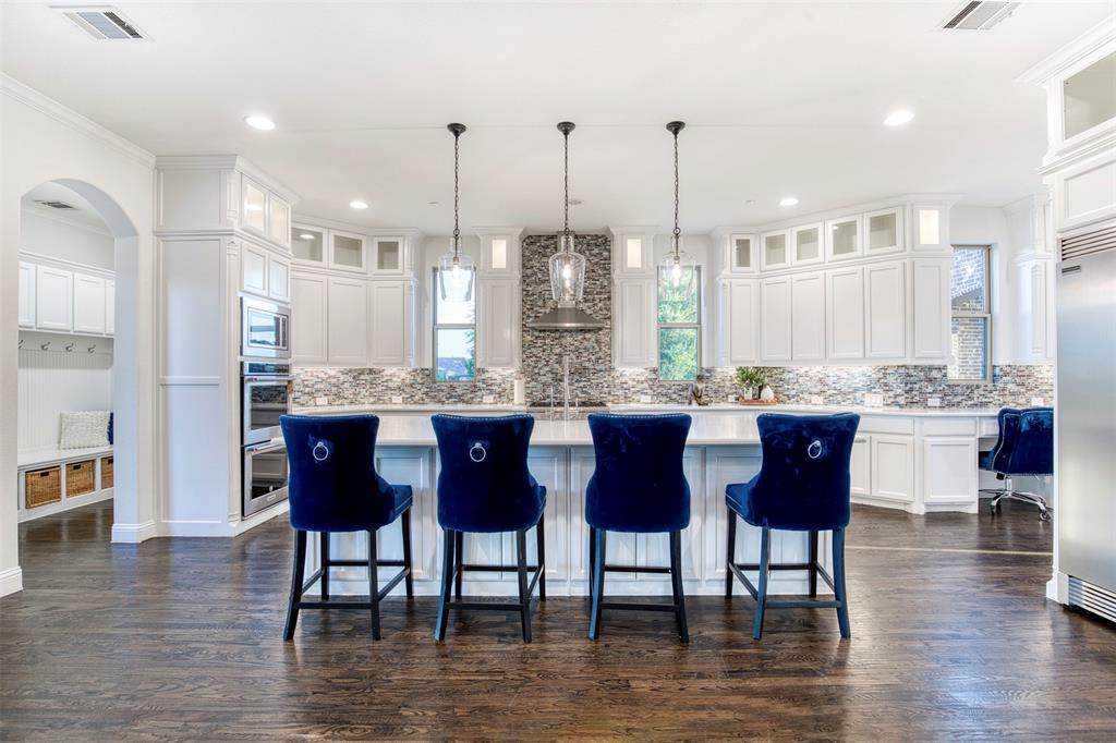 901 Inverness Court Lucas, TX 75002 - Photo 14 of 40 Kitchen with arched walkways, dark wood-style floors, glass insert cabinets, and an island with sink