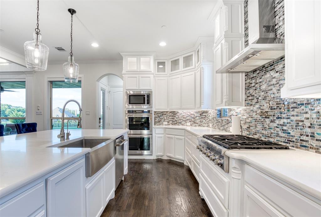 901 Inverness Court Lucas, TX 75002 - Photo 16 of 40 Kitchen with white cabinetry, stainless steel appliances, arched walkways, glass insert cabinets, and crown molding