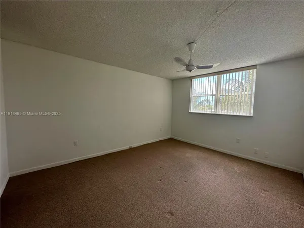 an empty room with windows and chandelier fan