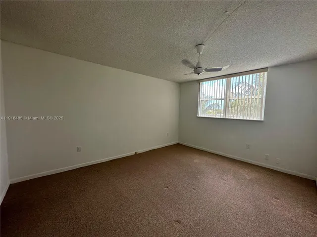 an empty room with windows and chandelier fan
