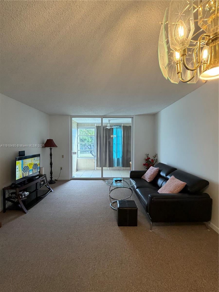 9101 Lime Bay Boulevard, Unit 302 Tamarac, FL 33321 - Photo 33 of 34 a living room with furniture and a chandelier