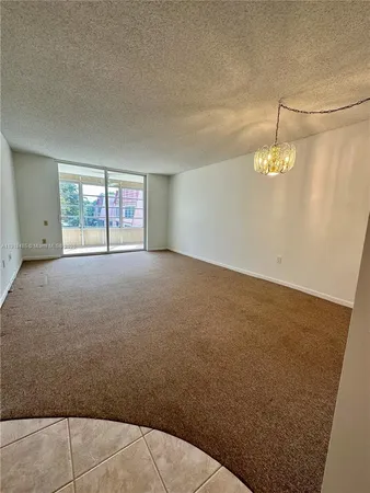 an empty room with a chandelier and wooden floor