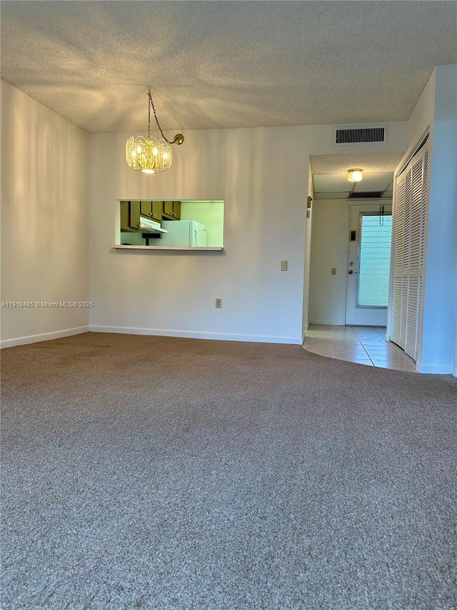 9101 Lime Bay Boulevard, Unit 302 Tamarac, FL 33321 - Photo 8 of 34 an empty room with a chandelier and wooden floor