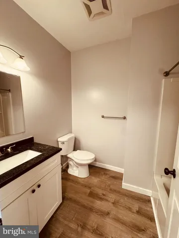 a bathroom with a granite countertop sink and a toilet