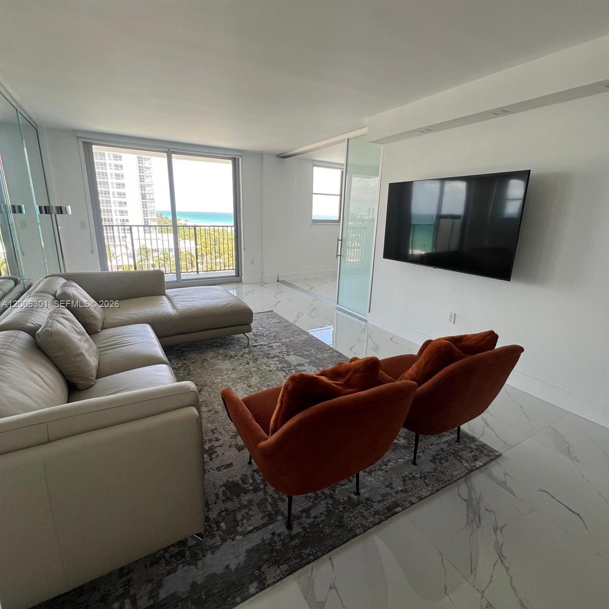 9273 Collins Avenue, Unit 606 Surfside, FL 33154 - Photo 1 of 25 a living room with furniture and a flat screen tv