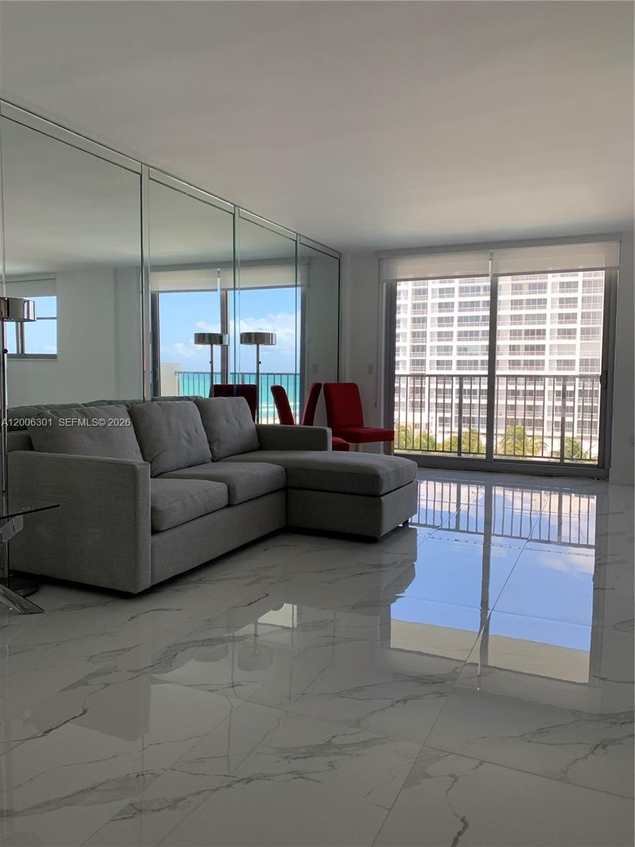 9273 Collins Avenue, Unit 606 Surfside, FL 33154 - Photo 2 of 25 a living room with furniture and a floor to ceiling window