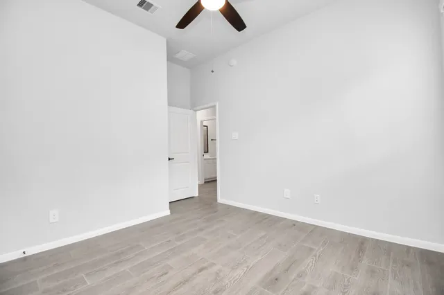 an empty room with ceiling fan and window