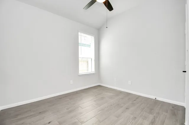 an empty room with ceiling fan and window