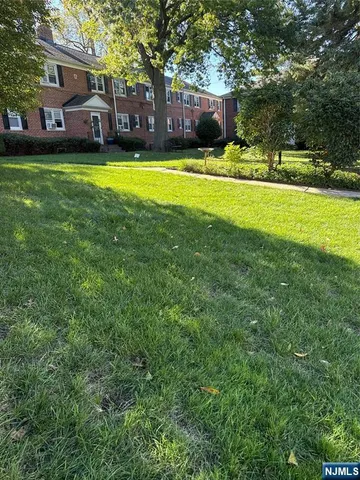 a front view of a house with a garden and trees