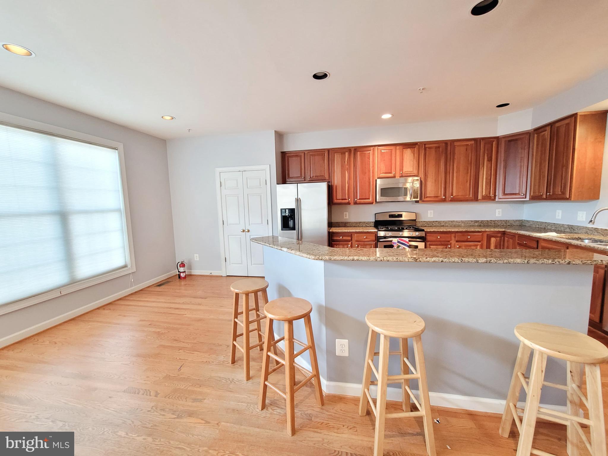 3960 Addison Woods Road Frederick, MD 21704 - Photo 5 of 19 a kitchen with stainless steel appliances granite countertop a stove top oven a sink a dining table and chairs with wooden floor