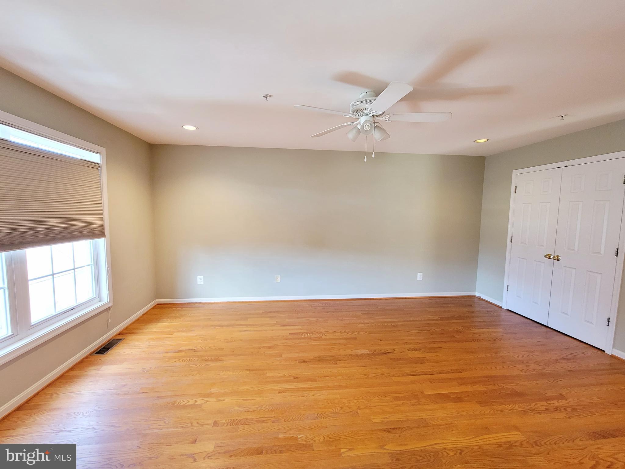 3960 Addison Woods Road Frederick, MD 21704 - Photo 9 of 19 an empty room with wooden floor and windows with curtains