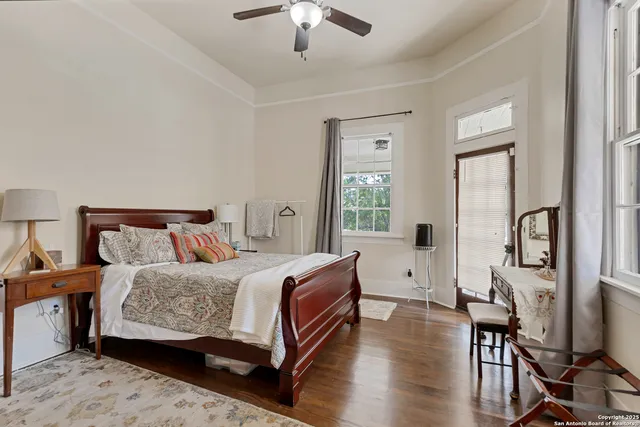 a bedroom with a bed a large window and wooden floor