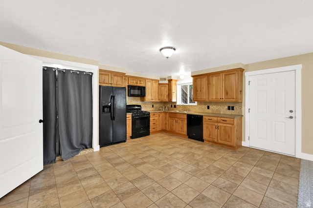 13658 South Fort Street Draper, UT 84020 - Photo 42 of 87 Kitchen featuring wood cabinetry, black appliances, tile flooring, and a tile backsplash