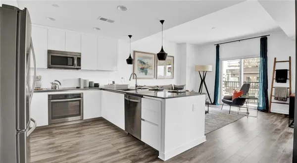 a kitchen with stainless steel appliances granite countertop a refrigerator a sink dishwasher a dining table and chairs with wooden floor