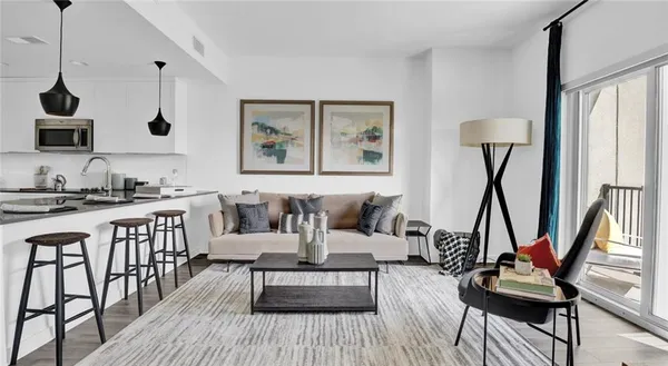 a living room with furniture a rug and a floor to ceiling window