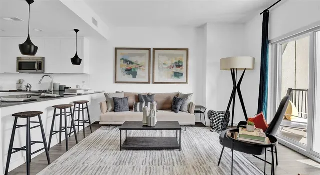 a living room with furniture a rug and a floor to ceiling window
