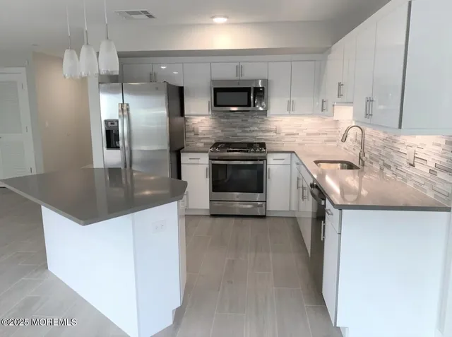 a kitchen with stainless steel appliances granite countertop a sink stove and refrigerator