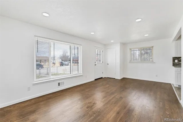 a view of an empty room with a window and wooden floor