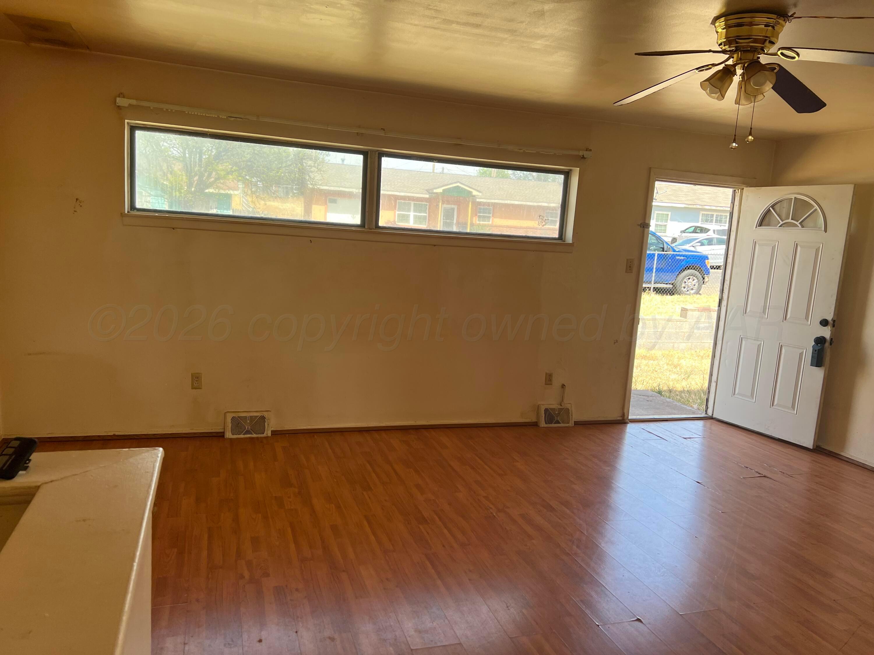 316 Poplar Street Amarillo, TX 79107 - Photo 2 of 8 a view of an empty room with wooden floor and a window