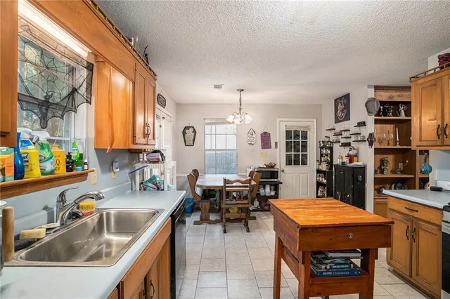 a kitchen with stainless steel appliances granite countertop a sink dishwasher and a refrigerator with wooden cabinets