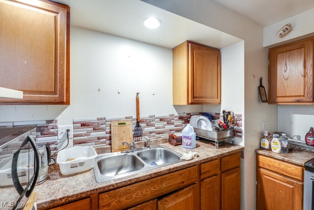 825 Rudyard Road Cleveland, OH 44110 - Photo 7 of 21 Kitchen with tasteful backsplash, light stone countertops, and sink