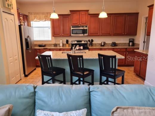 8923 Cuban Palm Road Kissimmee, FL 34747 - Photo 20 of 87 a living room with stainless steel appliances a couch a stove a sink a dining table and chairs