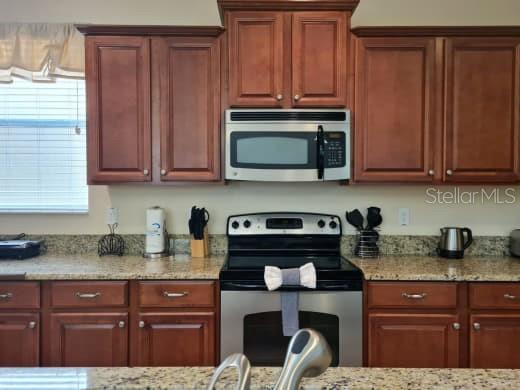 8923 Cuban Palm Road Kissimmee, FL 34747 - Photo 24 of 87 a kitchen with granite countertop wooden cabinets and a stove top oven