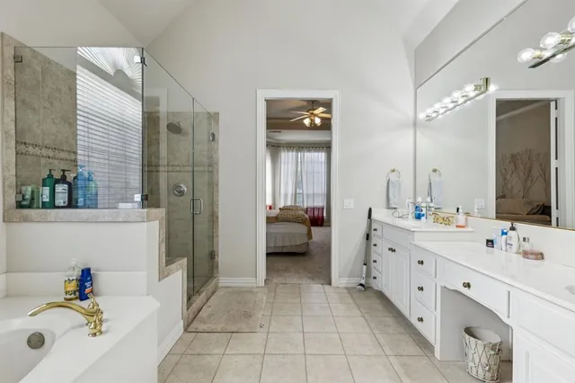 a en suite spacious bathroom with a tub double vanity and mirrors