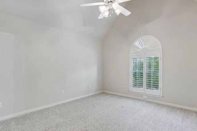 an empty room with a chandelier fan and windows