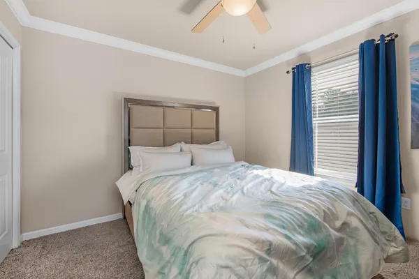 a large bed sitting in a bedroom next to a window and a chandelier