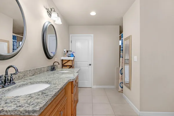 a bathroom with a granite countertop double vanity sink and a mirror