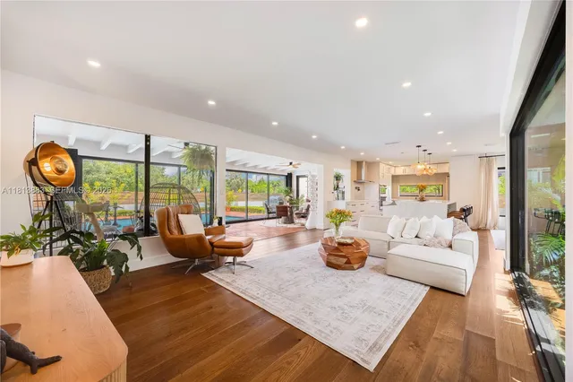 a living room with furniture floor to ceiling window and wooden floor