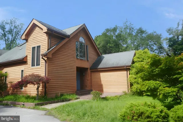 a view of a yard in front of a house with plants and large tree
