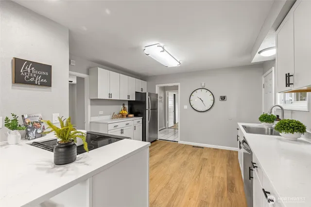 a kitchen with stainless steel appliances granite countertop a refrigerator a stove a sink a dining table and chairs with wooden floor