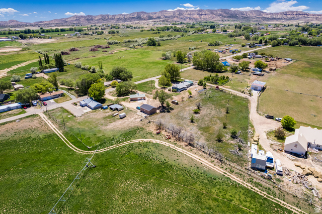 1043 East 4000th Street South Vernal, UT 84078 - Photo 24 of 31 Expansive rural landscape featuring multiple dwellings and agricultural buildings amidst green fields