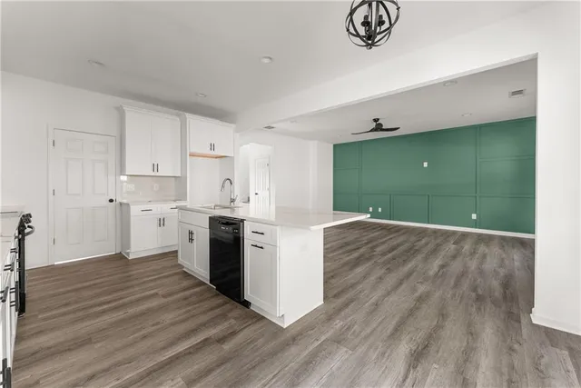 a kitchen with stainless steel appliances granite countertop a white cabinets and a wooden floor