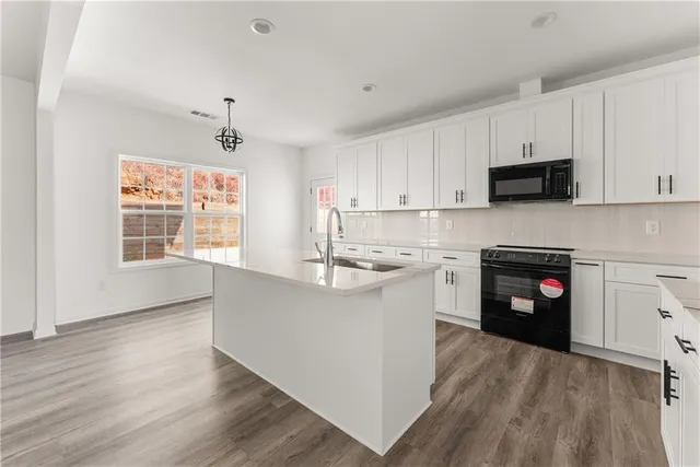 a kitchen with granite countertop a stove top oven a sink and white cabinets